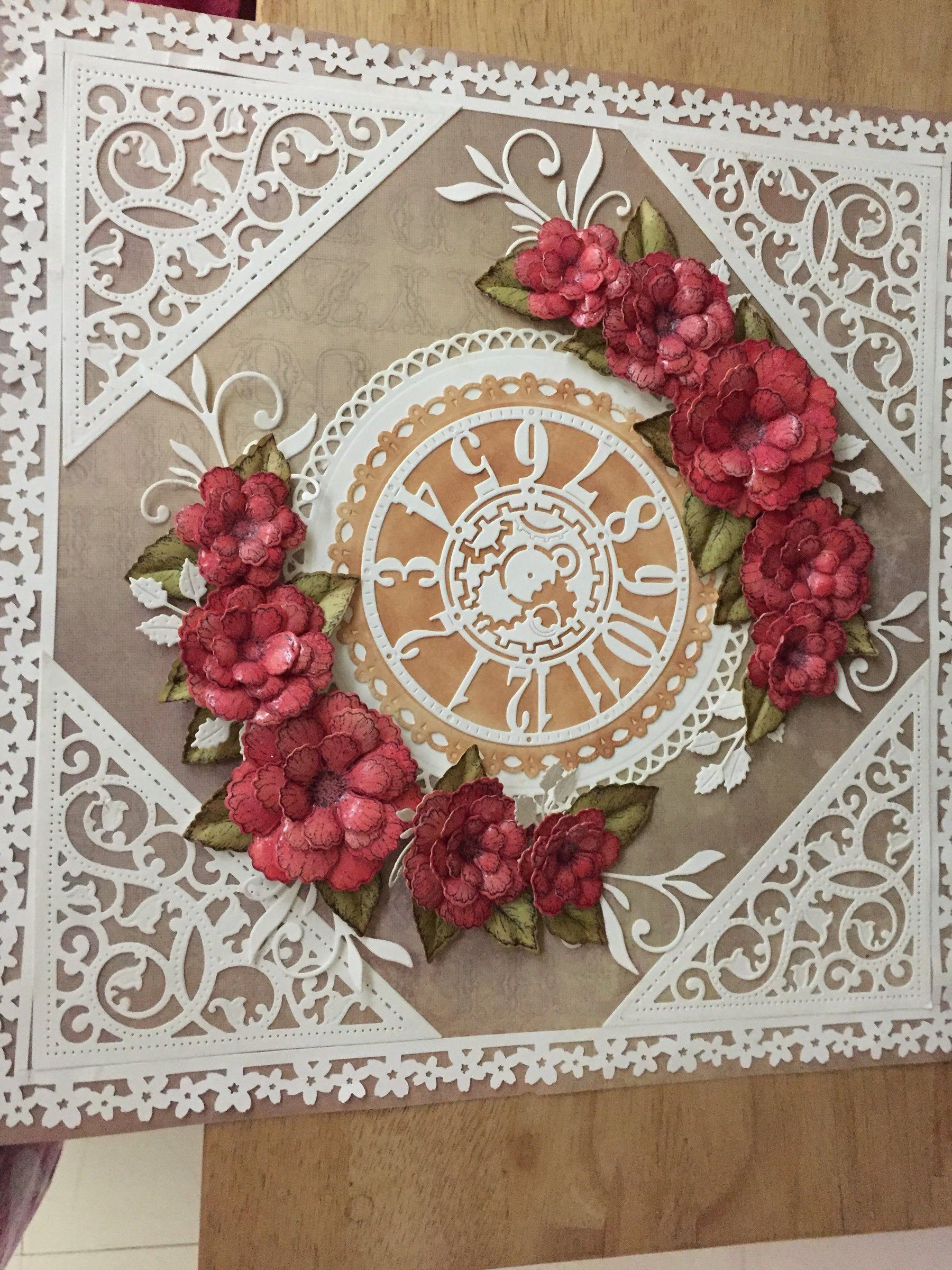 White filigree panel with a clock-face medallion at its centre, ringed by red paper roses