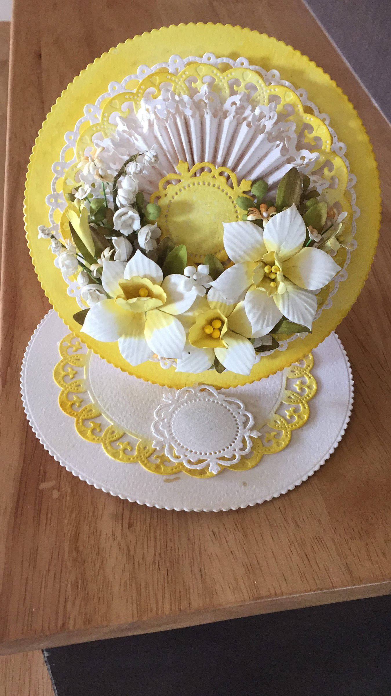 Standing paper centrepiece: a yellow scalloped disc layered with white lace and paper daffodils