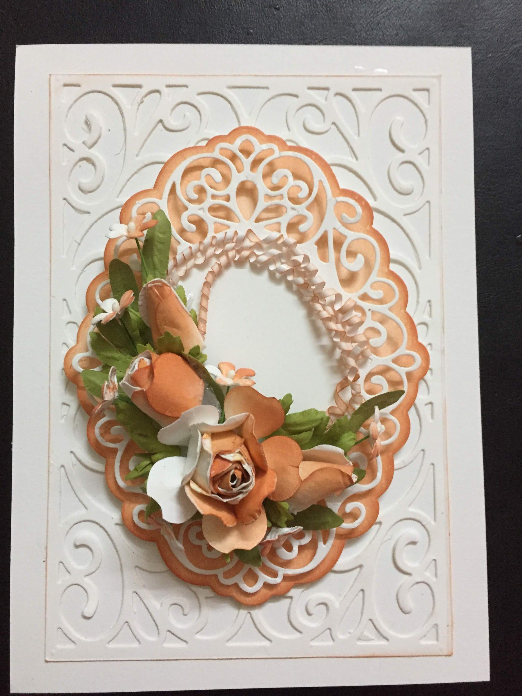 White embossed card with a peach lace oval and peach paper roses