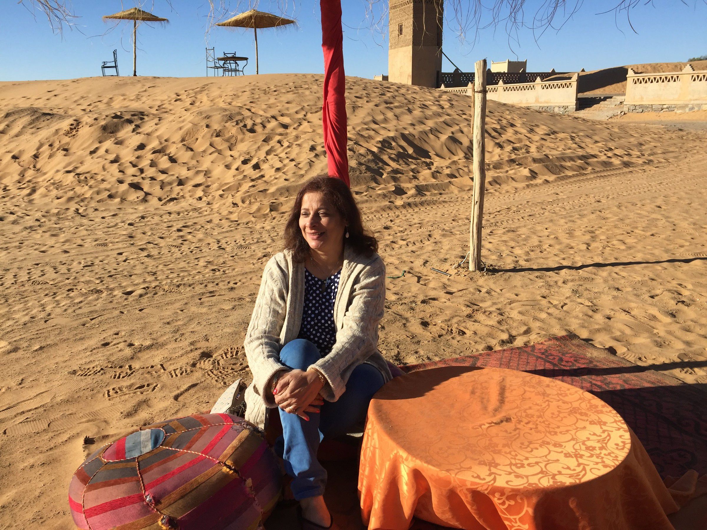 Mugdha seated on a cushion among sand dunes at a desert camp