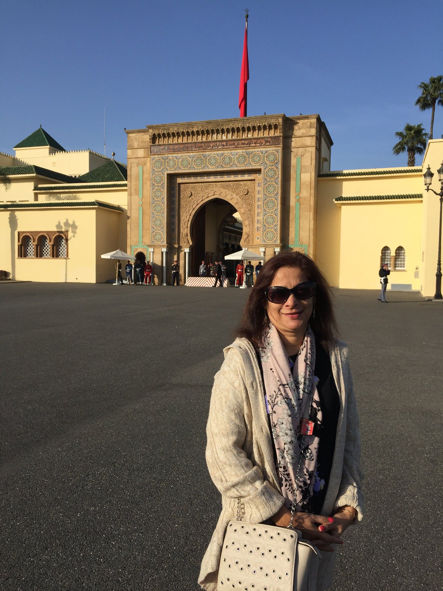 Mugdha in front of a palace gateway with gold doors and green-tiled roofs