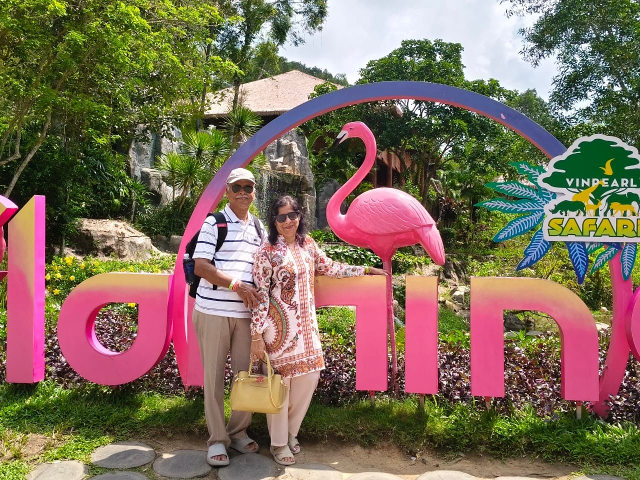 Mugdha and her husband beside a pink flamingo statue and a Vinpearl Safari sign