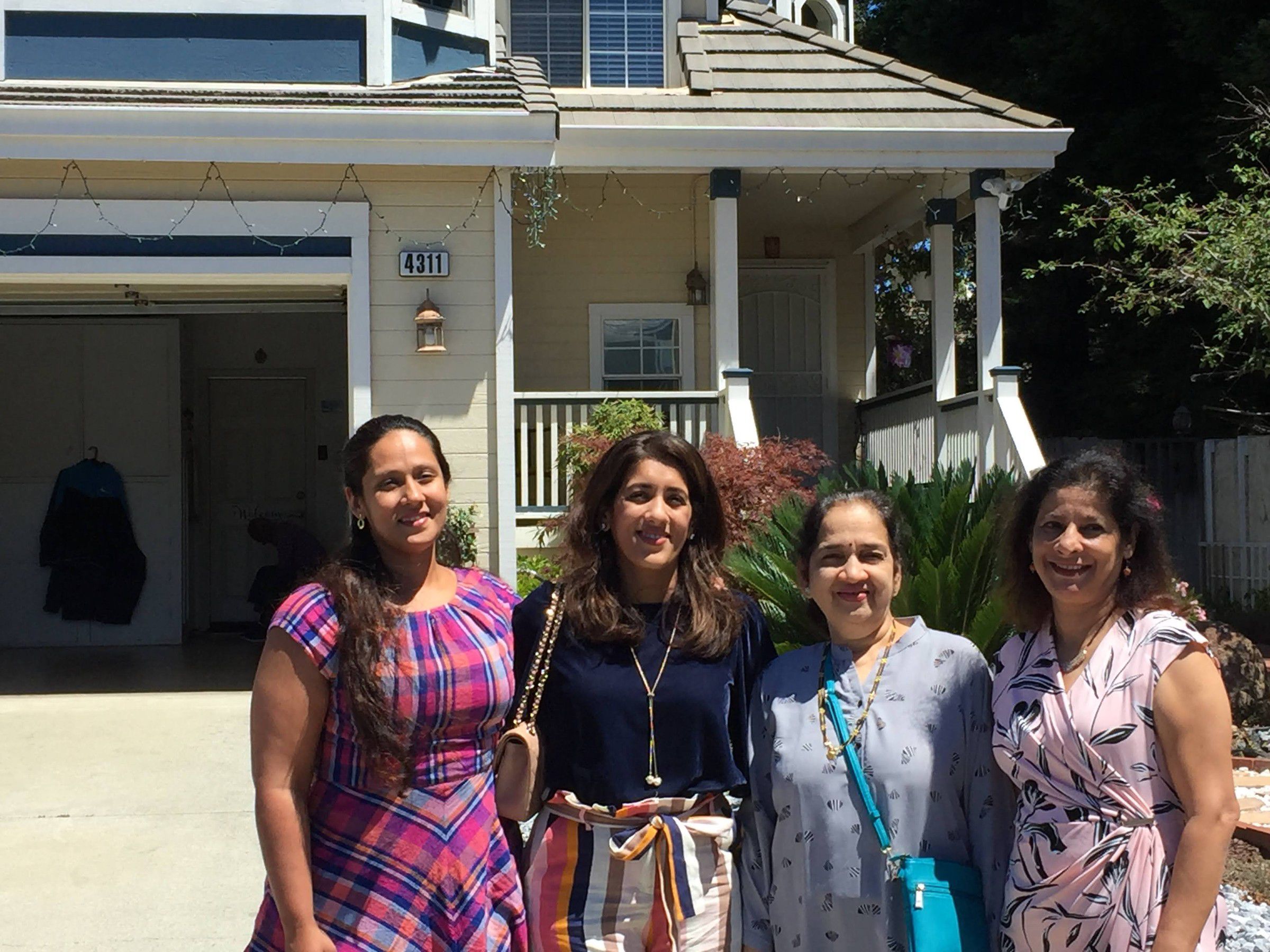 Mugdha with three women in front of a house